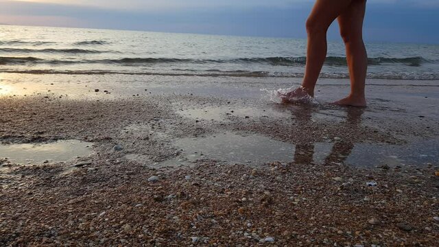 a woman walks on a sandy beach at sunset. a walk by the sea