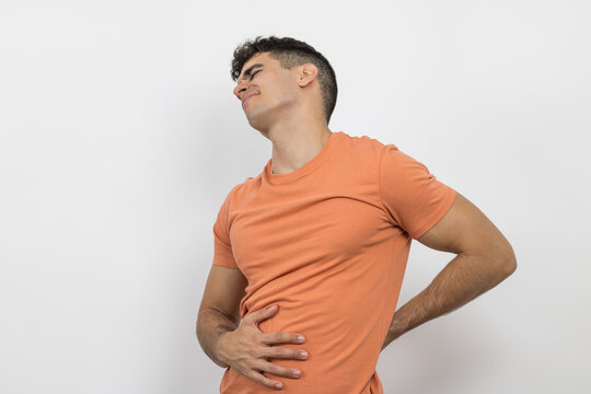 a young boy writhing in pain because his back hurts on a white background.