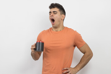 
a young boy yawning while drinking coffee on a white background.