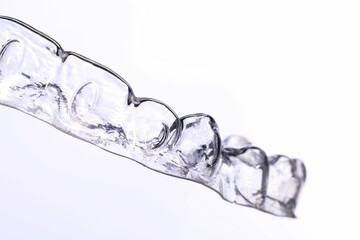 transparent tray for aligning teeth and bite in the hand of a doctor on a white background