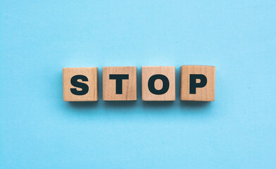 Word STOP. Wooden small cubes with letters isolated on blue background with copy space available. Concept image.
