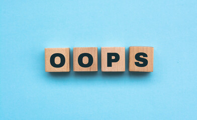 Word OOPS. Wooden small cubes with letters isolated on blue background with copy space available. Concept image.