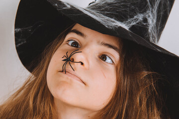 Girl's face in witch hat with spider halloween middle look
