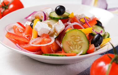 greek salad with tomatoes, olives, cucumbers,  pepper and soft feta cheese in a  plate