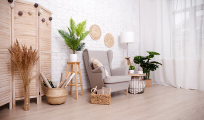 Scandinavian room with armchair, lamp and plants over brick wall