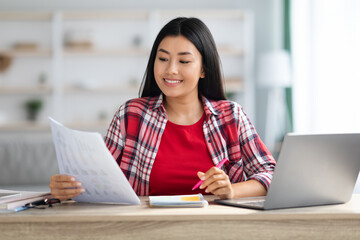 Home Office. Smiling Young Asian Businesswoman Working With Papers And Laptop
