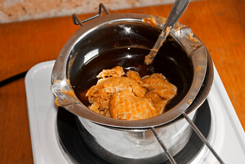 Wax in the process of melting in a metal dish on an electric stove. Candle making business .