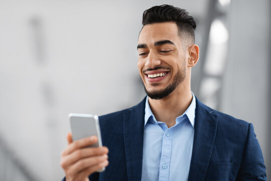 Online Communication. Portrait Of Handsome Middle Eastern Businessman In Suit Holding Smartphone - Powered by Adobe