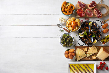 Spanish tapas on the right side of a white wooden table - obrazy, fototapety, plakaty