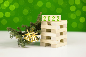 The inscription 2022 on the children's game with green spruce branch and bells. Green background