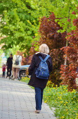 An elderly woman walking in the spring city