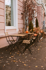 cafe terrace in autumn - table and chairs in the street with pumpkins decor