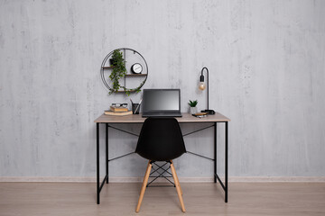 Workplace with laptop in office or home over grey wall
