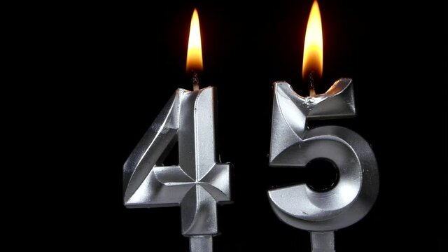 Burning silver birthday candles isolated on black background, number 45	