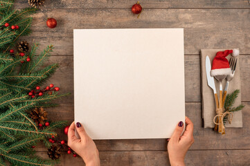 woman hands holds menu in her hands while sitting at Christmas dinner table. Christmas tree...