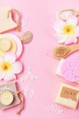Sea Salt Aroma Candles Face Sponges and Bamboo Face Brush Plumeria Flower Natural Soap Pink Background Copy Space SPA Frame Top View Wellness