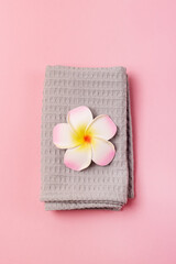 Obraz na płótnie Canvas Beautiful Spa Composition on Pink Background Gray Towel and Plumeria Flower Vertical
