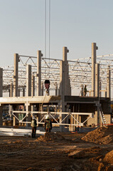 Fototapeta premium Crane build steel construction. Workers at industrial site.