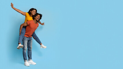 Cheerful black guy giving piggyback ride to his girlfriend