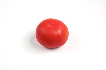 One red juicy tomato on a white plate.