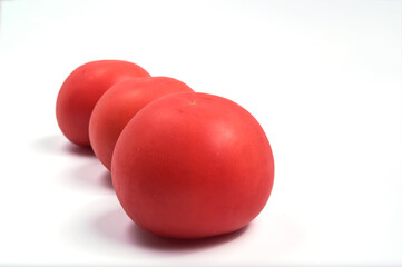 Three red juicy tomatoes in a row, on a white background