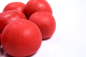Red tomatoes on a white background. Free space for text. Water drops on wet vegetables.