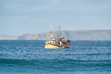 Yellow British fishing boat trawler alone in the English channel islands waters after leaving EU...