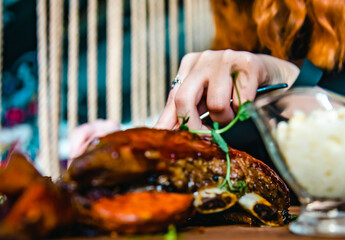 woman hands with fork and knife eating meat ribs in cafe