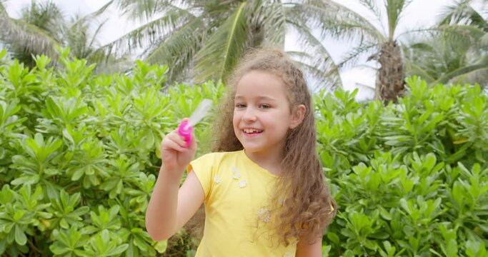 Portrait of funny lovely little girl blowing soap bubbles.