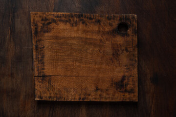 Empty chopping board on dark wooden background.