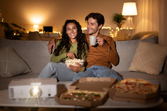 Couple Enjoying Movie Eating Popcorn And Pizza At Home