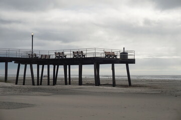 Fototapeta premium Weathered Wooden Pier Extending over Beach with Ocean and Sky