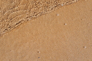 Fototapeta na wymiar Small wave with sand in a beach