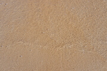 Small wave with sand in a beach