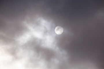 Fototapeta na wymiar Disk of the sun shining through dark clouds.
