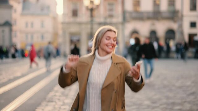 Portrait of happy senior woman enjoying success on phone at city street. Closeup joyful woman reading good news on cellphone in slow motion. . High quality 4k footage