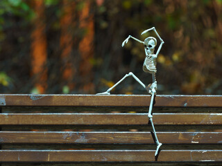 Photograph of a skeleton on the bench in the public park at night. Agressive skeleton toy.