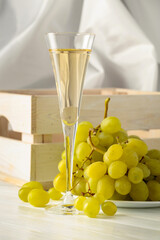 Glass of white wine and grape cluster.
