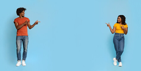 Beautiful black man and woman pointing at copy space