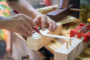 carpenter using a red pencil to draw a line on wood at workshop.,DIY maker and woodworking concept. selective focus