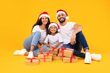 Happy Arab Family Sitting Among Xmas Presents Boxes, Yellow Background