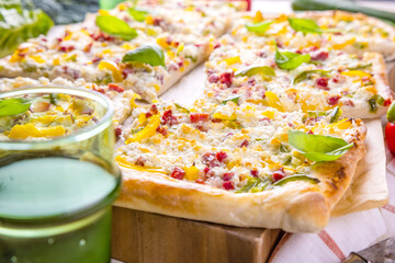 Frischer geschnittener Flammkuchen auf hölzernem Untergrund.