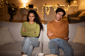 Unhappy Couple After Quarrel Crossing Hands Sitting On Sofa Indoor