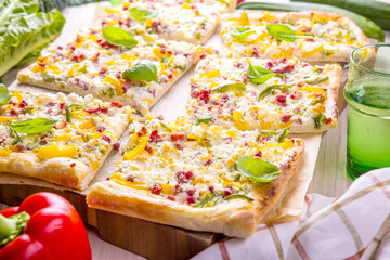 Frischer geschnittener Flammkuchen auf hölzernem Untergrund.