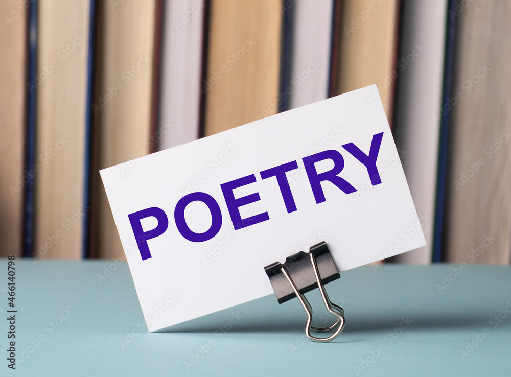 Wall mural a white card with the text poetry stands on a clip for papers on the table against the background of