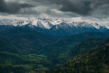 Fototapeta premium Snow covered Bavarian Alps with dramatic dark clouds, green forest at Jachenau near Lake Walchensee, Bavaria.