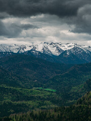 Fototapeta premium Snow covered Bavarian Alps with dramatic dark clouds, green forest at Jachenau near Lake Walchensee, Bavaria.