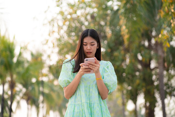 Fototapeta premium Beautiful asian women use cell phone outdoor park