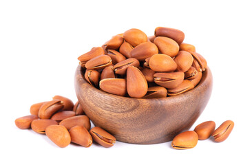 Pine nuts in wooden bowl, isolated on white background. Heap of roasted pine nuts in shells.