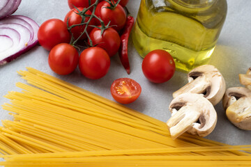 Spaghetti, tomatoes, champignons, onions, and olive oil on the table